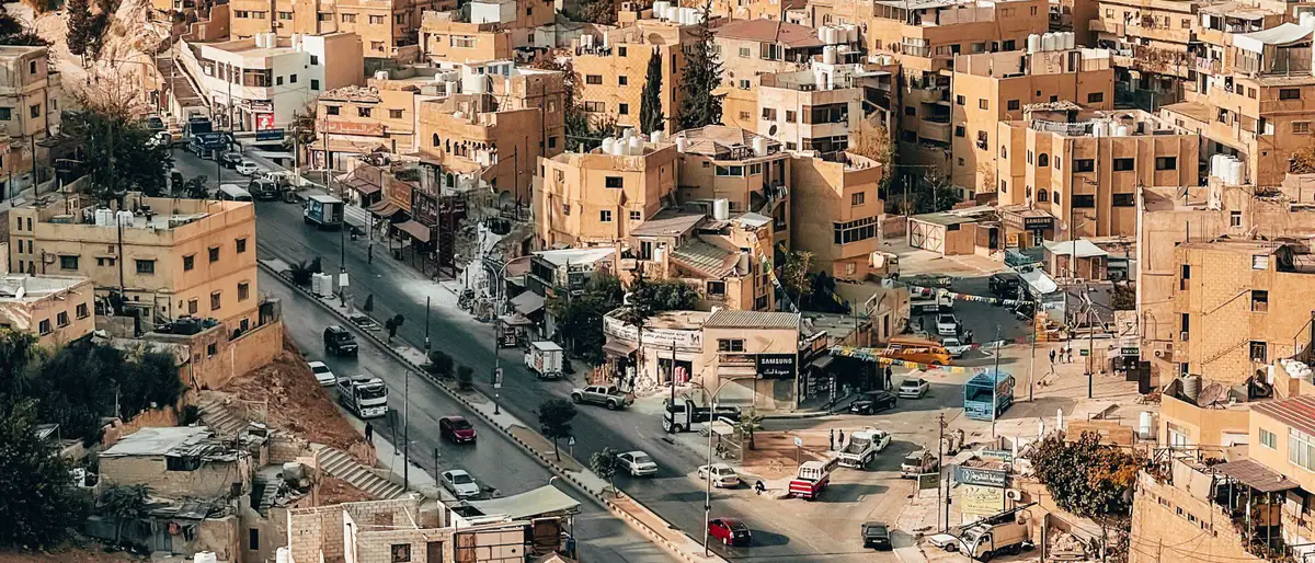 من نحن: شارع في وسط عمّان تحيط به البيوت الحجرية على سفوح الجبال